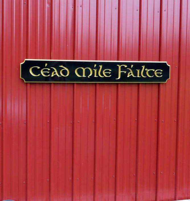 Cead Mile Failte carved on black and gold quarterboard it in gaelic font