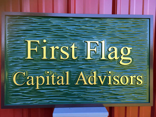 Rectangular shape company sign painted green, brown, and gold with First Flag Capital Advisors carved on it