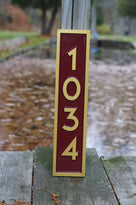 Vertical address sign with numbers 1034 painted red and gold