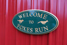 Neighborhood welcome sign with fox and dog carved on it painted green and gold