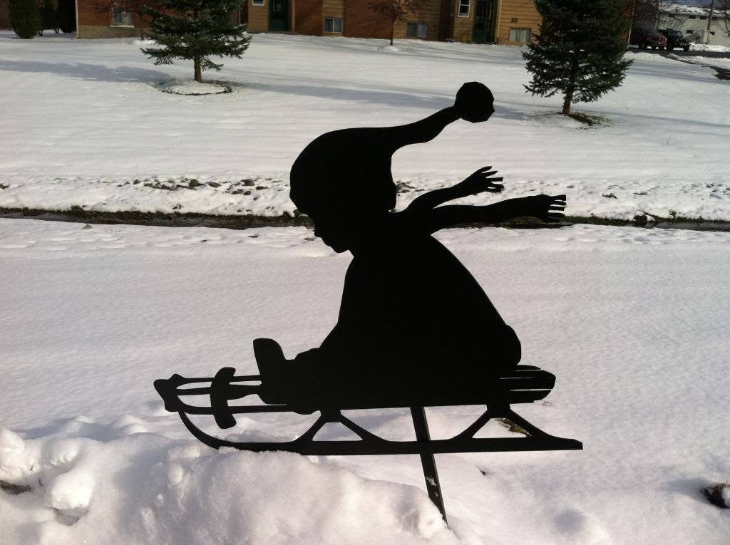 Silhouette of child going down hill in snow in yard