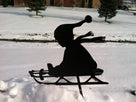 Silhouette of child going down hill in snow in yard